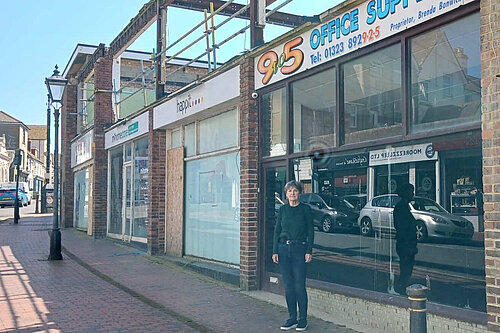 Councillor Carolyn Lambert standing in front of some rather down at heel shops with the remnants of what was the first floor of the building above them.